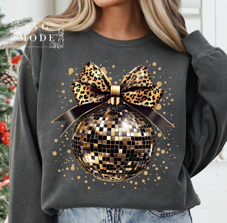 May include: A gray sweatshirt with a gold disco ball ornament and a leopard print bow. The ornament is surrounded by gold glitter.