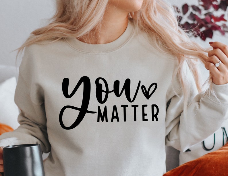 May include: A light gray sweatshirt with the text "you matter" in black cursive lettering with a small heart symbol next to the word "you".