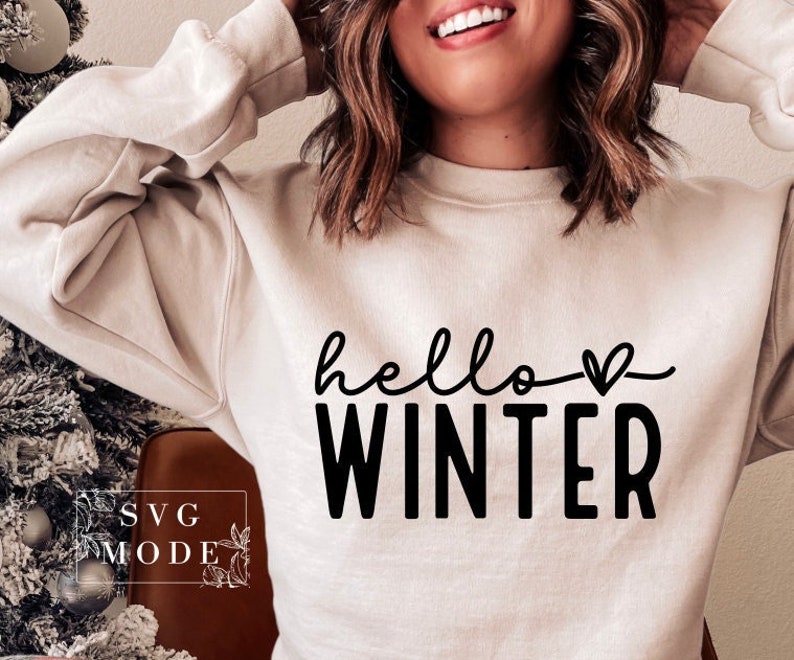 May include: A white sweatshirt with the text "hello winter" in black lettering with a small heart above the word "winter".