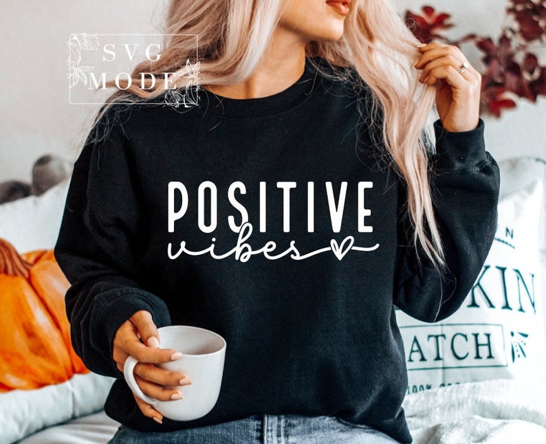 Peut inclure: Sweat-shirt noir avec un texte blanc qui dit "POSITIVE vibes" avec un petit symbole de c&oelig;ur.
