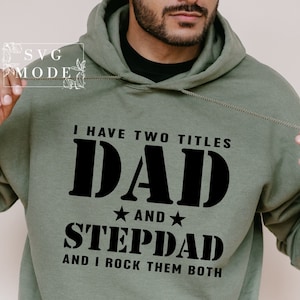 May include: A green hooded sweatshirt with the text "I have two titles DAD and STEPDAD and I rock them both" printed in black.