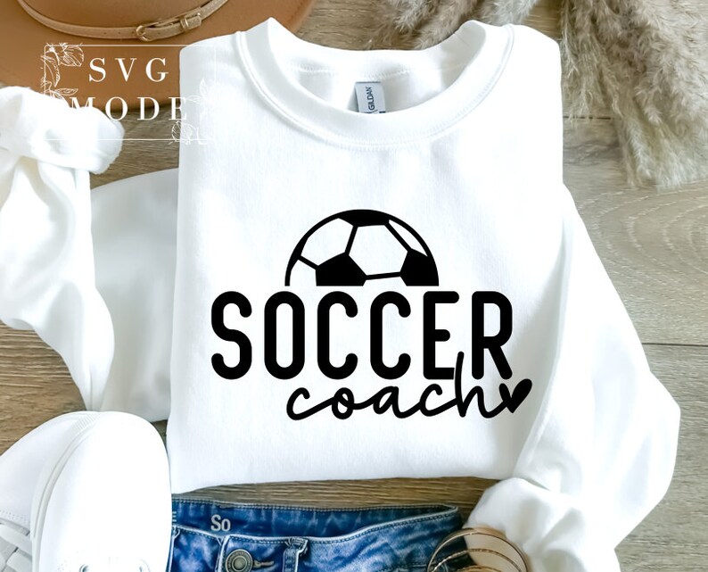 May include: White sweatshirt with a black football graphic and the text "SOCCER coach" with a heart.