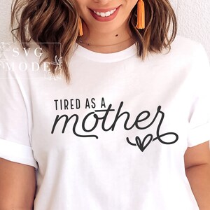 May include: White t-shirt with the text "Tired as a mother" in black cursive font with a small heart underneath.