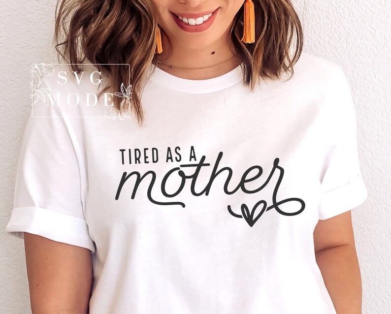 May include: White t-shirt with the text "Tired as a mother" in black cursive font with a small heart underneath.