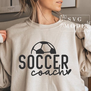 May include: A beige sweatshirt with a black football graphic and the text "SOCCER coach" with a heart.