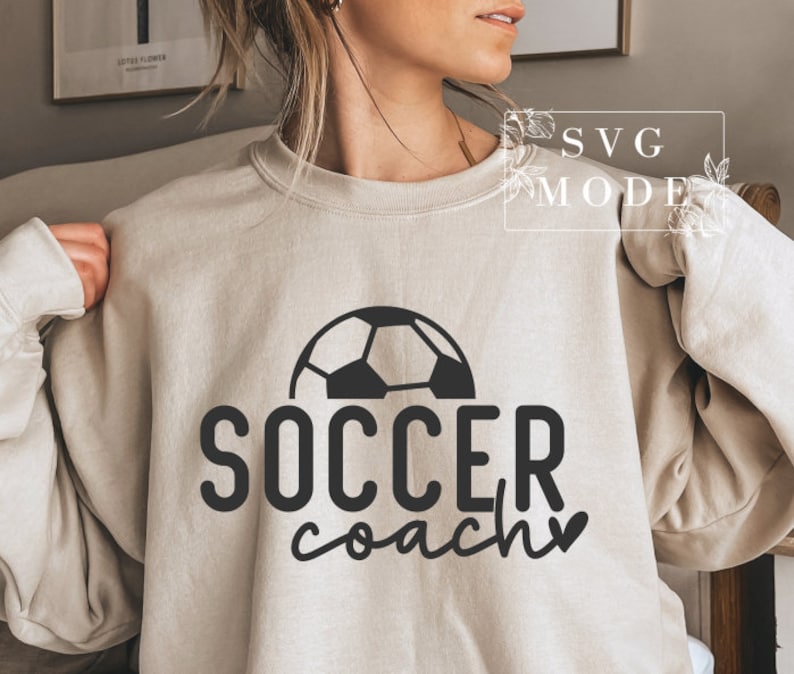 May include: A beige sweatshirt with a black football graphic and the text "SOCCER coach" with a heart.