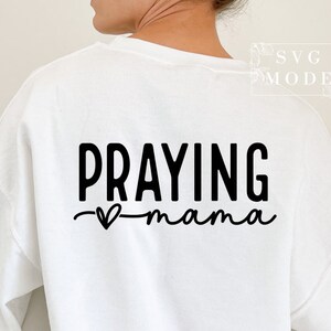 May include: White sweatshirt with black text that reads "Praying mama" with a small heart symbol.