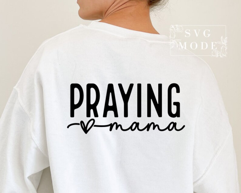 May include: White sweatshirt with black text that reads "Praying mama" with a small heart symbol.