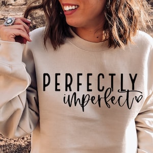 May include: A beige sweatshirt with the text "PERFECTLY imperfect" in black lettering with a small heart symbol.