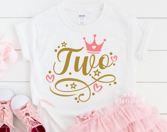 May include: White t-shirt with gold lettering that says "Two" and a pink crown with a pink heart in the center. The shirt is decorated with pink hearts and gold stars.