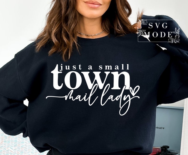 Peut inclure: Sweat-shirt noir avec un texte blanc qui dit "just a small town mail lady" avec un petit c&oelig;ur.