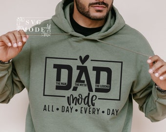 May include: Green hooded sweatshirt with a black graphic that says "DAD" with the words "The Man", "The Myth", and "The Legend" underneath. The graphic also includes a heart and the word "mode" written in cursive. The text "ALL DAY EVERY DAY" is printed below the graphic.