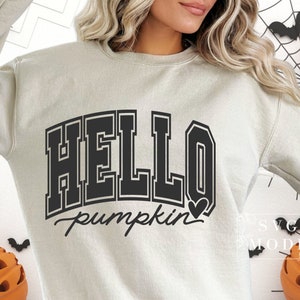 Może przedstawiać: Jasnobeżowa bluza z napisem "HELLO pumpkin" w kolorze czarnym z małym sercem po słowie "pumpkin".