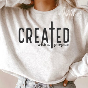 May include: A gray sweatshirt with the text "CREATED with a purpose" and a cross graphic.