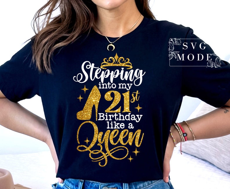 Pode incluir: Camiseta preta com um design dourado brilhante. O design inclui o texto "Stepping into my 21st Birthday like a Queen" com um salto alto e um gr&aacute;fico de coroa. A camiseta &eacute; de gola redonda.
