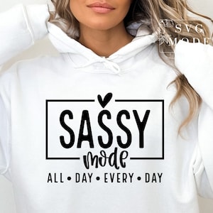 May include: White hoodie with black text that reads "Sassy Mode All Day Every Day" with a small heart above the word "Sassy".