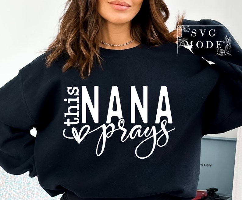 May include: Black sweatshirt with white text that reads "This Nana prays" with a heart symbol.
