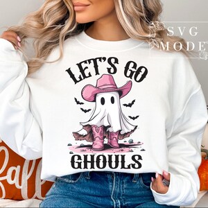 Może przedstawiać: Biała bluza z nadrukiem ducha w r&oacute;żowym kowbojskim kapeluszu i butach. Na bluzie widnieje napis "Let's Go Ghouls".