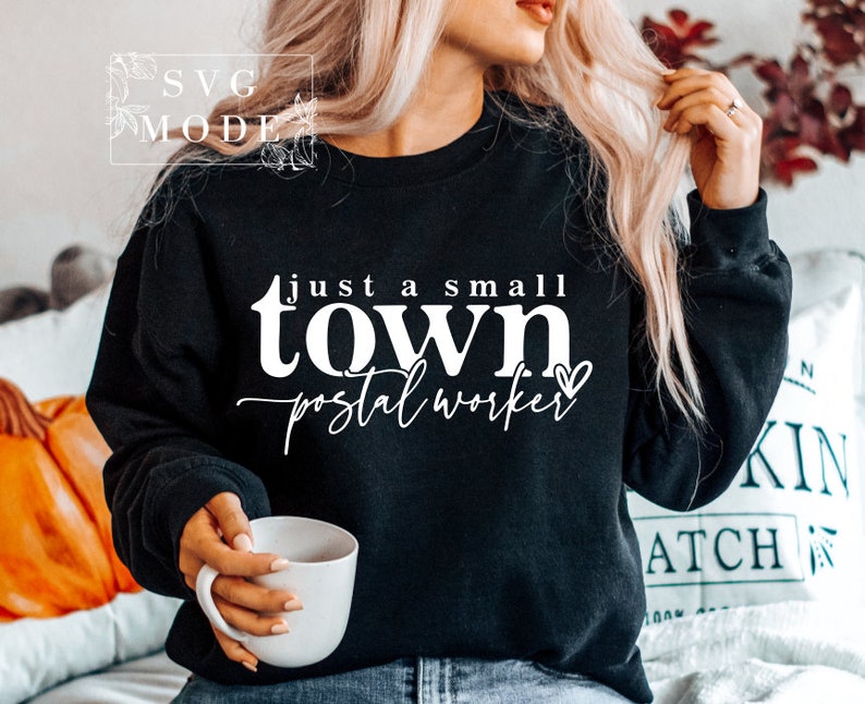 May include: A black sweatshirt with white text that reads "Just a small town postal worker" with a small heart icon.