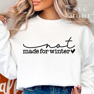 May include: White sweatshirt with black text that reads "not made for winter" with a small black heart.