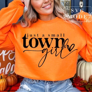 May include: Orange sweatshirt with the text "just a small town girl" in black lettering with a small heart.