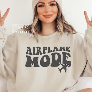 Puede incluir: Una sudadera beige con el texto "AIRPLANE MODE" en una fuente retro, con un peque&ntilde;o gr&aacute;fico de avi&oacute;n debajo del texto.