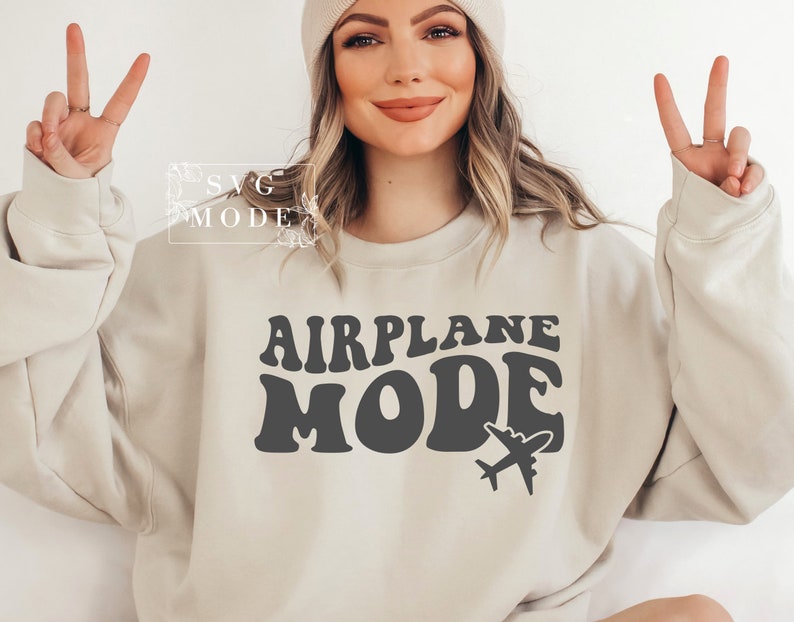 Puede incluir: Una sudadera beige con el texto "AIRPLANE MODE" en una fuente retro, con un peque&ntilde;o gr&aacute;fico de avi&oacute;n debajo del texto.