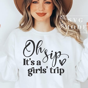 K&ouml;nnte beinhalten: Wei&szlig;er Pullover mit schwarzem Text, der "Oh sip it's a girls' trip" mit einem kleinen Herzsymbol lautet.