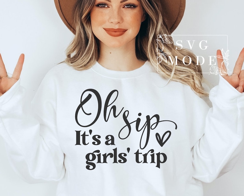 K&ouml;nnte beinhalten: Wei&szlig;er Pullover mit schwarzem Text, der "Oh sip it's a girls' trip" mit einem kleinen Herzsymbol lautet.