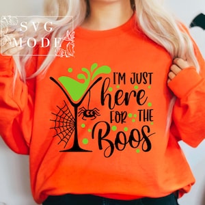 May include: Orange sweatshirt with a black and green graphic design of a martini glass with a spider and web, and the text "I'm just here for the boos".