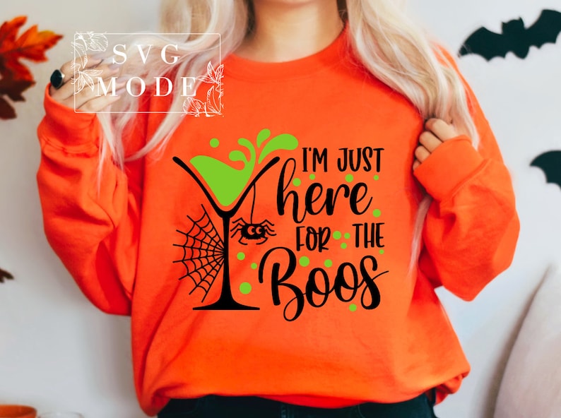 May include: Orange sweatshirt with a black and green graphic design of a martini glass with a spider and web, and the text "I'm just here for the boos".