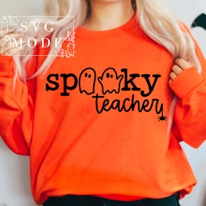 May include: Orange sweatshirt with the text "spooky teacher" in black with three ghost illustrations and a small spider.