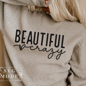 Pode incluir: Uma camisa de moletom cinza com o texto "BEAUTIFUL crazy" em letras pretas com um pequeno s&iacute;mbolo de cora&ccedil;&atilde;o.