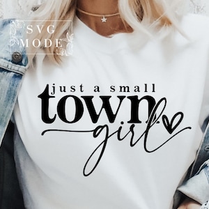May include: White t-shirt with black text that reads "just a small town girl" with a small heart symbol.
