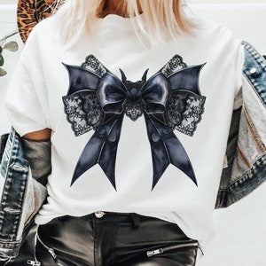 May include: A white t-shirt with a large black lace bow design. The bow is made of satin ribbon and has a delicate lace trim.