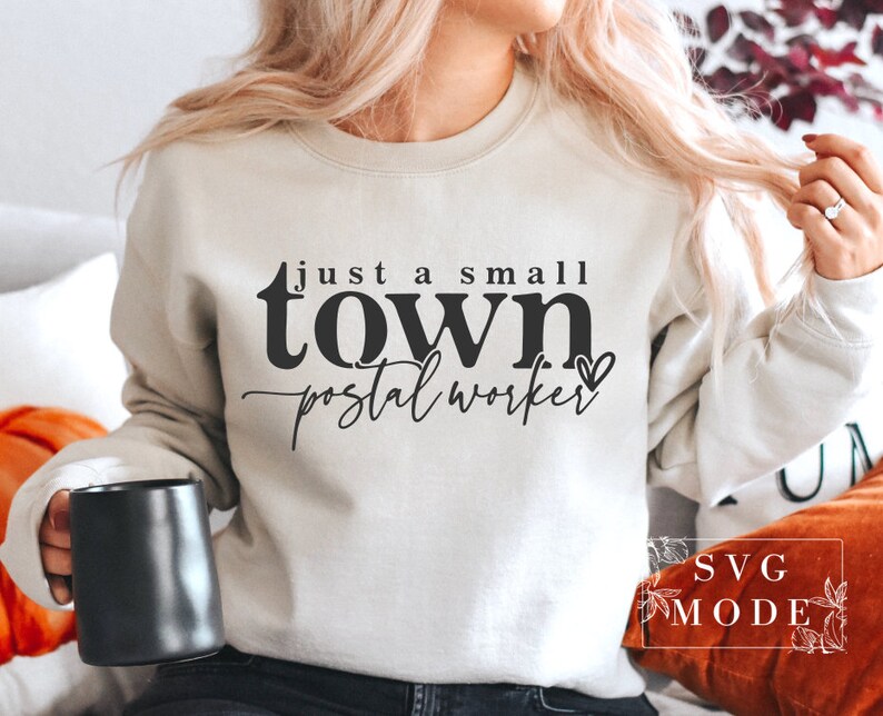 May include: A white sweatshirt with the text "just a small town postal worker" in black lettering with a small heart symbol.