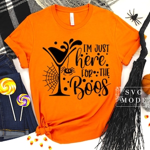 May include: Orange t-shirt with a black graphic of a martini glass with a spider web and spider, and the text "I'm just here for the boos".