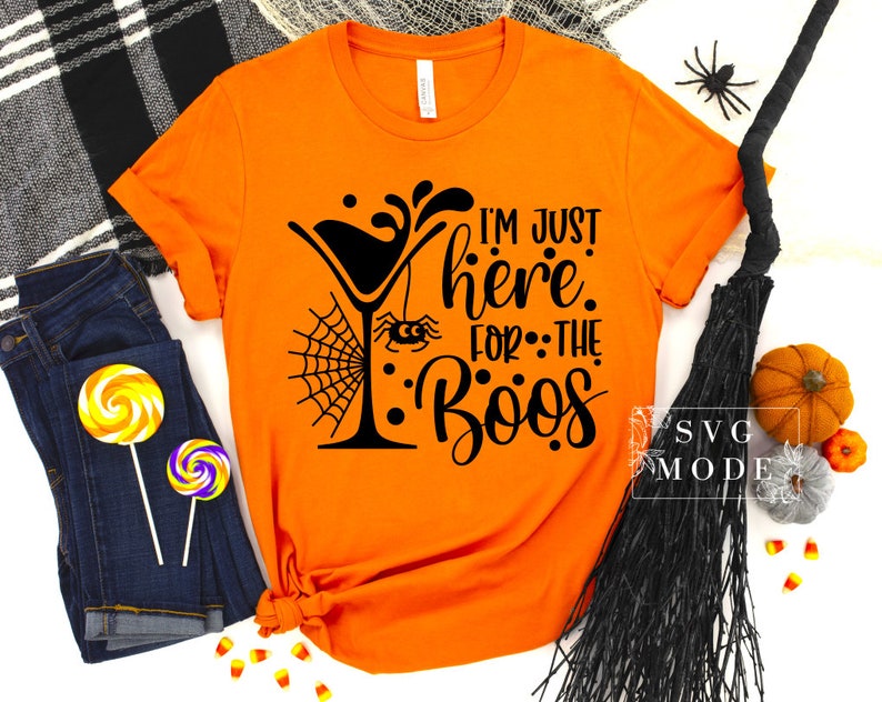 May include: Orange t-shirt with a black graphic of a martini glass with a spider web and spider, and the text "I'm just here for the boos".
