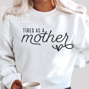 May include: White sweatshirt with the text "TIRED AS A mother" in black cursive lettering with a small heart at the end.