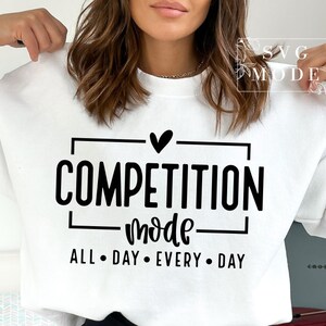 May include: White sweatshirt with black text that reads "Competition Mode" with a heart above the word "Competition" and "All Day Every Day" below the word "Mode".