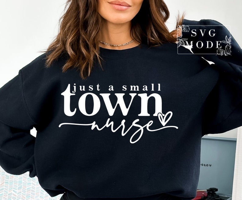 May include: Black sweatshirt with white text that reads "just a small town nurse" with a small heart after the word "nurse".
