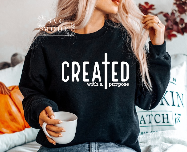 May include: Black sweatshirt with white text that reads "CREATED with a purpose" and a white cross.