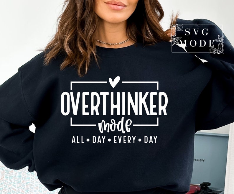 May include: Black sweatshirt with the text "OVERTHINKER mode ALL DAY EVERY DAY" in white. The text is inside a white rectangle with a heart above the word "OVERTHINKER". The sweatshirt is a crew neck style.