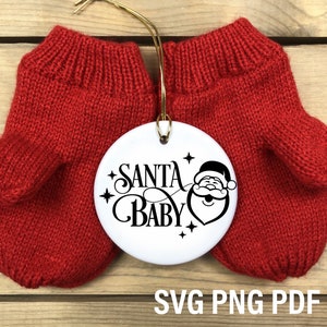 May include: Red knitted mittens with a white round ornament that says "Santa Baby" with a cartoon Santa Claus face.