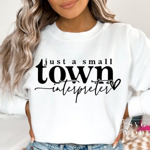 May include: White sweatshirt with black text that reads "just a small town interpreter" with a small heart symbol.