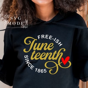 Pu&ograve; includere: Una felpa con cappuccio nera con un design dorato che dice "Free-ish Juneteenth Since 1865" con un cuore rosso.