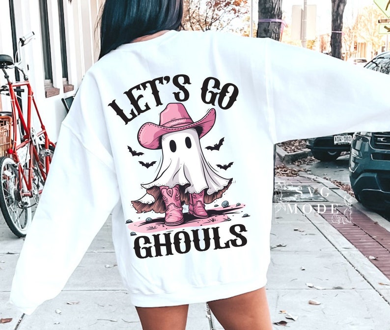 Może przedstawiać: Biała bluza z nadrukiem ducha w r&oacute;żowym kowbojskim kapeluszu i butach. Na bluzce widnieje napis "Let's go ghouls".