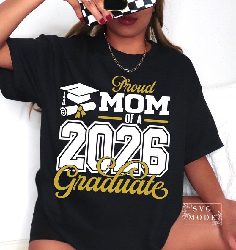 Puede incluir: Camiseta negra con el texto "Proud MOM of a 2026 Graduate" en letras blancas y doradas. El dise&ntilde;o incluye un birrete y un diploma. Un regalo perfecto para una madre orgullosa.