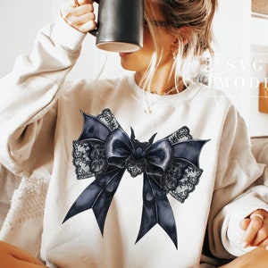 May include: A white sweatshirt with a black and white lace bow design. The bow is large and has a satin-like texture.