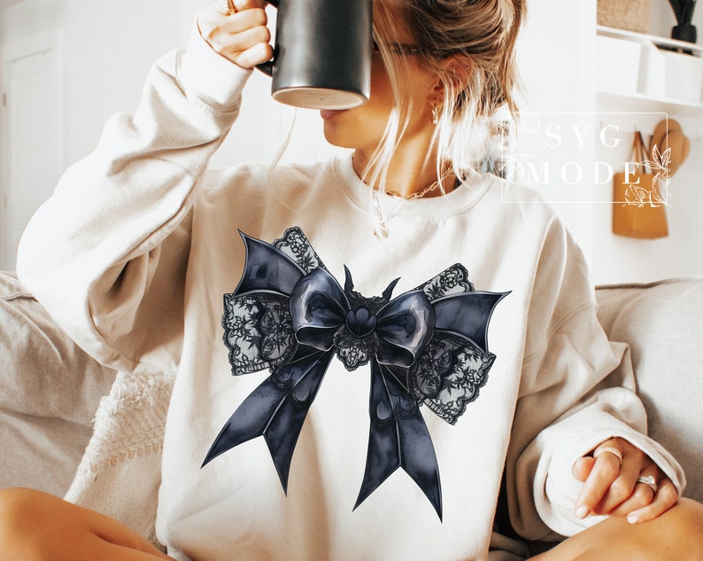 May include: A white sweatshirt with a black and white lace bow design. The bow is large and has a satin-like texture.